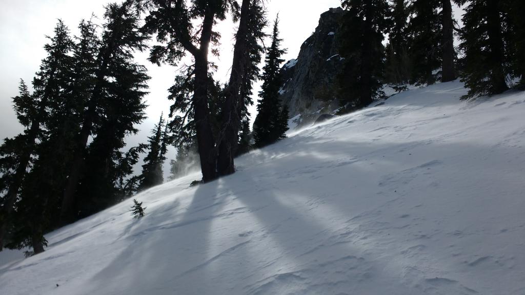  Blowing snow near summit of Rubicon Peak. Fresh <a href="/avalanche-terms/wind-slab" title="A cohesive layer of snow formed when wind deposits snow onto leeward terrain. Wind slabs are often smooth and rounded and sometimes sound hollow." class="lexicon-term">wind slabs</a> below summit pinnacle on E <a href="/avalanche-terms/aspect" title="The compass direction a slope faces (i.e. North, South, East, or West.)" class="lexicon-term">aspect</a>. 