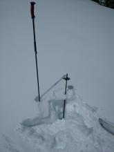 A dusting of new snow on top of a breakable crust with wet snow down to the handle of the inverted pole at 7800 ft. 