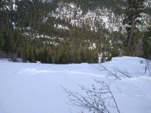 Pit location above avalanche path below. Trim line and runout zone just visible in background.
