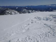 The torn up snow is where the victim parked their snowmobile. The footprints lead to the edge where the cornice broke.