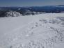 The torn up snow is where the victim parked their snowmobile. The footprints lead to the edge where the cornice broke.